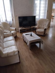 sala de estar con muebles blancos y TV de pantalla plana en Maison chaleureuse, en Saint-Jean-dʼAngély