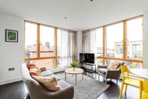 a living room with a couch and chairs and a tv at Comfortable Modern Flat in Shoreditch in London