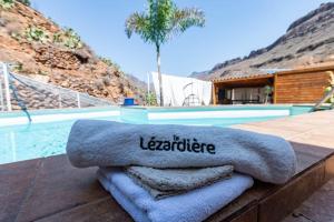 サン・バルトロメにあるStudio Bed-room in quiet montain - swimming pool, jacuzzi, wifi, tv outdoor chill out - La Lézardièreのスイミングプールの横に置いたタオル