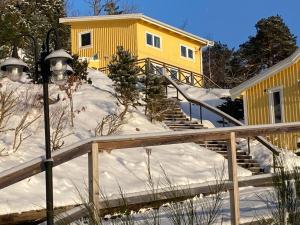 una casa gialla nella neve con una scala di Riddarhuset a Ljungskile