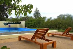 2 sillas de madera sentadas junto a una piscina en Cabaña, hospedaje Vegetariano en San Esteban