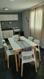 una cocina con mesa y sillas blancas, mesa y sillón en Casa en Potrero de Garay con pileta a 100mt Rio San Pedro in 