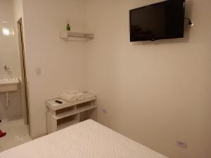 um quarto com uma cama e uma televisão na parede em Suíte Studio 3 Enseada Tortuga Mobiliada no Guarujá