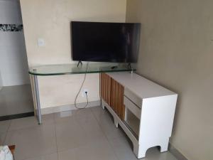 a living room with a tv and a white desk at Quitinete para casal in Brasília