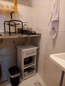 a bathroom with a sink and a shelf next to a toilet at Suíte Studio 3 Enseada Tortuga Mobiliada in Guarujá