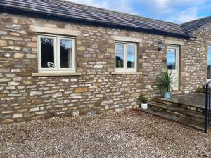 a stone house with a bench and windows at The Annexe in Middleham
