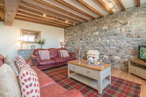 a living room with a couch and a stone wall at Granar-Soch in Abersoch