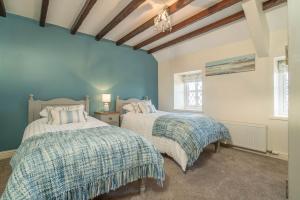 two beds in a room with blue walls at Granar-Soch in Abersoch