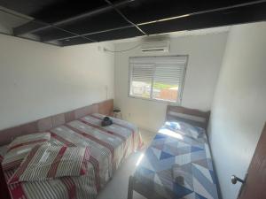 Habitación pequeña con cama y ventana en Pousada Munhoz, en São Gabriel