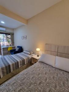una habitación de hotel con 2 camas y una silla en De la Mora Hostal, en Fernando de la Mora