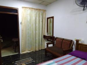 1 dormitorio con cama, silla y espejo en Wilpattu Buma Homestay, en Pahala Maragahawewa