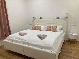 a white bed with two heart pillows on it at Andy Apartmán Jáchymov in Jáchymov