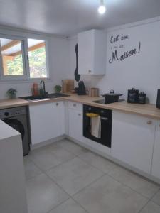 Una cocina con gabinetes blancos y un fregadero. en les lau, en Sainte-Anne