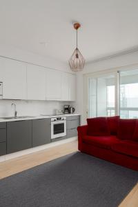 uma sala de estar com um sofá vermelho e uma cozinha em New LUXUS 3BR Helsinki Home em Helsinque