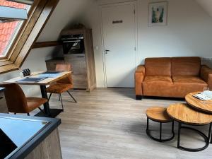 ein Wohnzimmer mit einem Sofa, Tischen und Stühlen in der Unterkunft Ruim appartement met sauna, Zuidstraat 125 in Westkapelle in Westkapelle