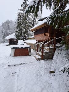 a snow covered log cabin with a snow covered yard at Dom nad jeziorem Ublik z sauną i jacuzzi in Ublik