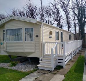 a cream colored tiny house with a white fence at CHANNI in Prestatyn