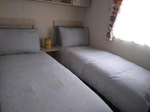 two beds in a small room with a window at CHANNI in Prestatyn