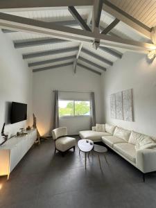 a living room with a white couch and a tv at La Maison Calebasse in Saint-François