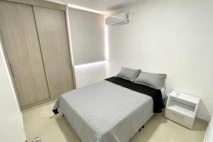 um pequeno quarto com uma cama num quarto branco em Apartamento con vista a las montañas, cerca Centro Comercial Mayales em Valledupar