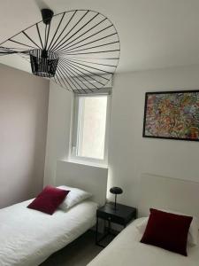 a bedroom with two beds and a large chandelier at A few steps from BASEL with Balcony and free parking in Saint-Louis