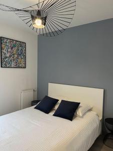 a bedroom with a white bed with blue pillows at A few steps from BASEL with Balcony and free parking in Saint-Louis