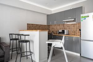 a kitchen with black and white cabinets and a white refrigerator at One Bedroom Apartment Near Arbat In The Heart of Almaty in Almaty