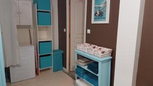 a walk in closet with a blue table and shelves at Sous la charmille. in Cerisy-la-Salle