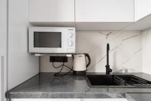 a kitchen counter with a microwave and a sink at Two Bedroom Apartment In The Heart of Almaty in Almaty