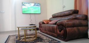 salon z brązową skórzaną kanapą i stołem w obiekcie Apparts AWA - Meublé haut standing Yaoundé Centre Ville w mieście Jaunde
