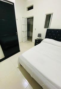 1 dormitorio con cama blanca y puerta negra en Alojamientos Z.V, en Tumaco
