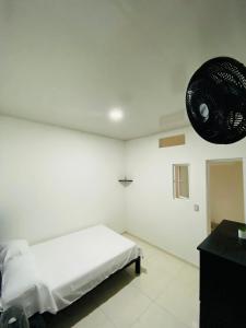 a white bedroom with a bed and a fan at Alojamientos Z.V in Tumaco