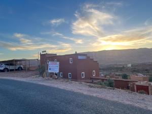 a building on the side of a road with a sign at Kasbah Tigmi El Janoub in Aït Benhaddou
