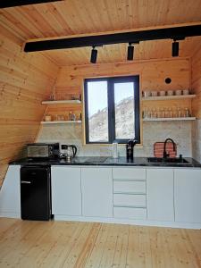 una cucina con armadietti bianchi e frigorifero nero di Arsha View a Kazbegi