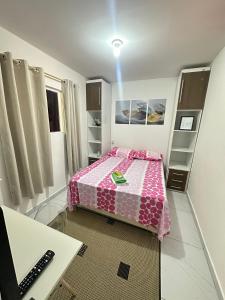 um pequeno quarto com uma cama rosa e uma secretária em Aero-Quarto Aconchegante em Bayeux