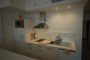 a white kitchen with a sink and a microwave at Resort Sitges Apartment in Sitges