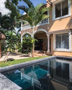 a swimming pool in front of a house with a palm tree at Hostal Tunich Naj & Hotel in Valladolid