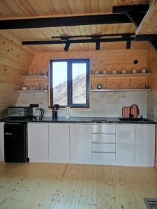 una cocina con armarios blancos y una ventana en Arsha View en Kazbegi