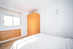 バレンシアにあるÁtico de Lujo Plaza Ayuntamientoの白いベッドと木製キャビネット付きのベッドルーム1室が備わります。