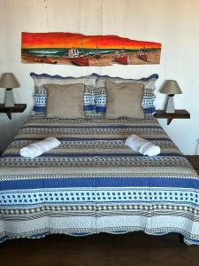 een groot bed met blauwe en witte lakens en kussens bij Frente playa in Punta Del Diablo