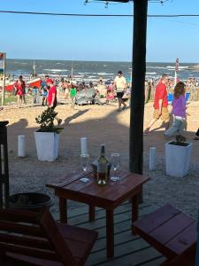 een picknicktafel met wijnglazen en mensen op het strand bij Frente playa in Punta Del Diablo