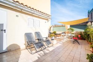 eine Terrasse mit 3 Stühlen und einem Tisch auf einem Gebäude in der Unterkunft Ático de Lujo Plaza Ayuntamiento in Valencia