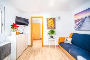 Una sala de estar con un sofá azul y un televisor en Ático de Lujo Plaza Ayuntamiento, en Valencia