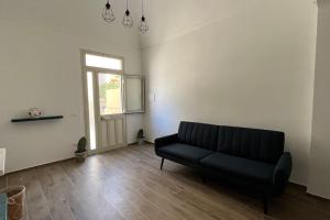 ein Wohnzimmer mit einem schwarzen Sofa und einem Fenster in der Unterkunft Casa indipendente in Tonnara di Bonagia