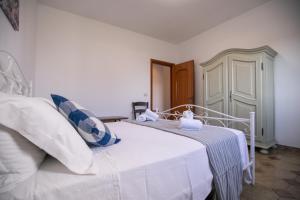 a bedroom with a white bed with a blue and white blanket at Villa del Mirto a 300mt dalla spiaggia, parcheggio privato, animali ammessi in Torre Santa Sabina