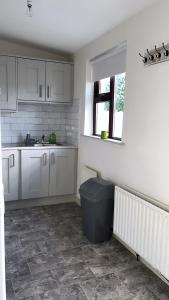 a kitchen with white cabinets and a trash can at The Chroma Cottage in Cock Hill