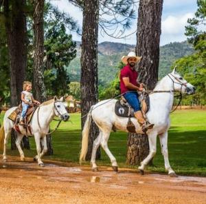 Un uomo e un bambino che cavalcano a cavallo di Hotel Boutique Coração Aberto a Capitólio