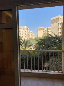 a balcony with a view of a palm tree and buildings at Luxurious, fully furnished and well equipped apartment with modern amenities, stunning views, and convenient location for remote work or studying from home in Madinaty