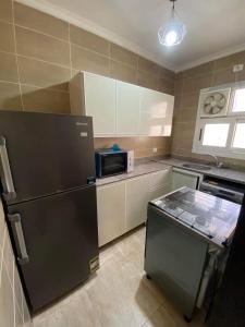 a kitchen with a black refrigerator and a microwave at Luxurious, fully furnished and well equipped apartment with modern amenities, stunning views, and convenient location for remote work or studying from home in Madinaty