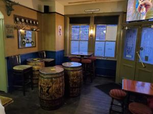 a bar with wooden stools and tables and windows at The Queens Arms Hotel in Acomb